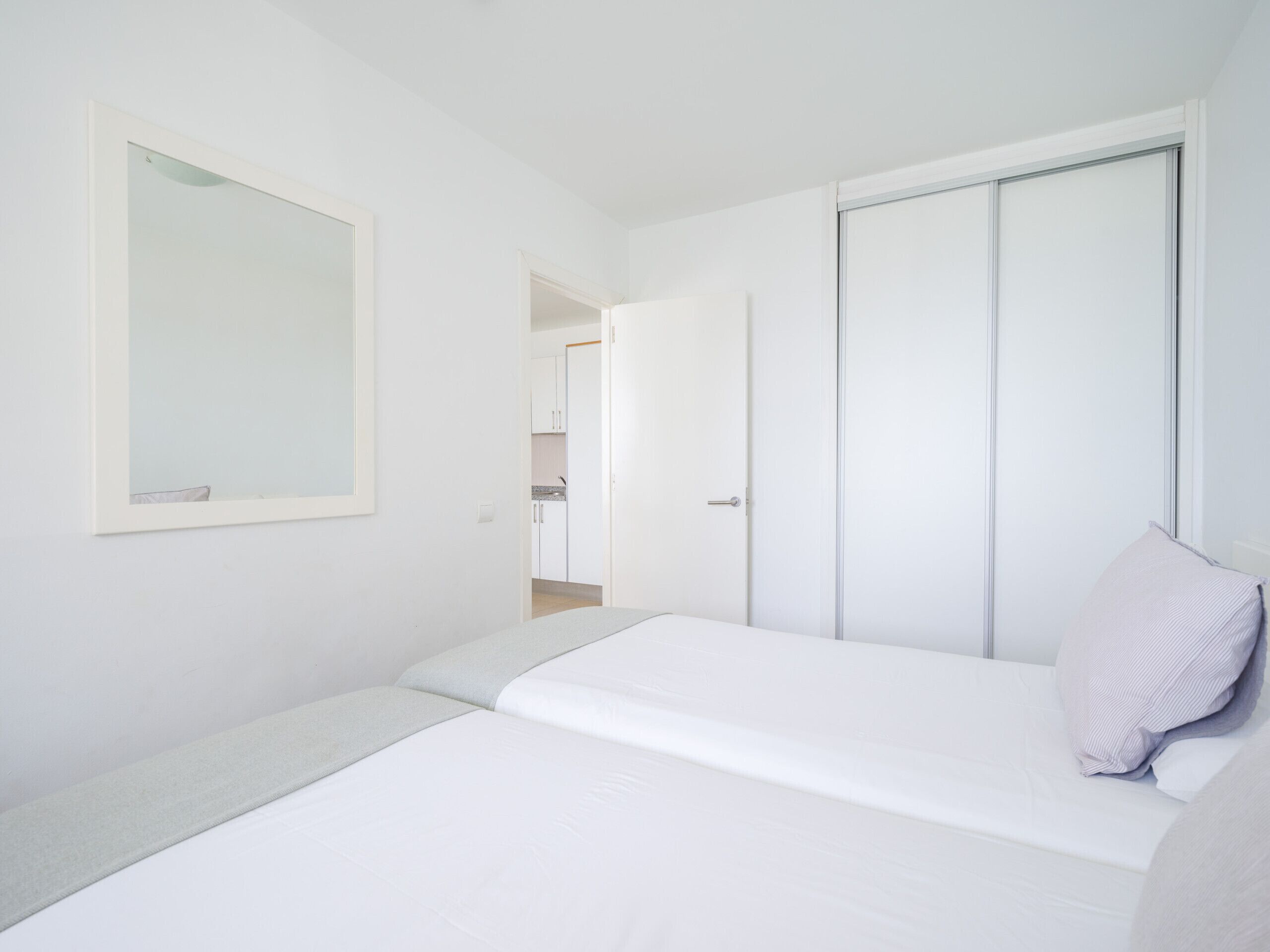 Quarto com uma cama, um guarda-roupa, um espelho e uma porta que dá para um banheiro.