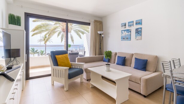 A modern living room with a sofa, armchair, coffee table, and dining area.