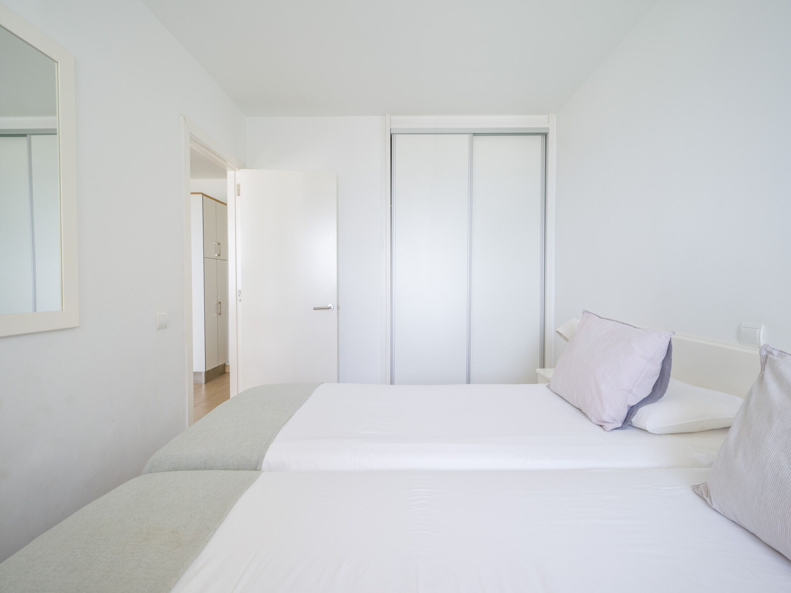 A bedroom with a bed, a wardrobe, and a mirror.
