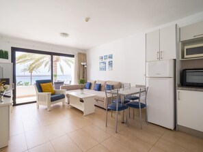 A modern apartment with a balcony, a dining area, and a kitchenette.