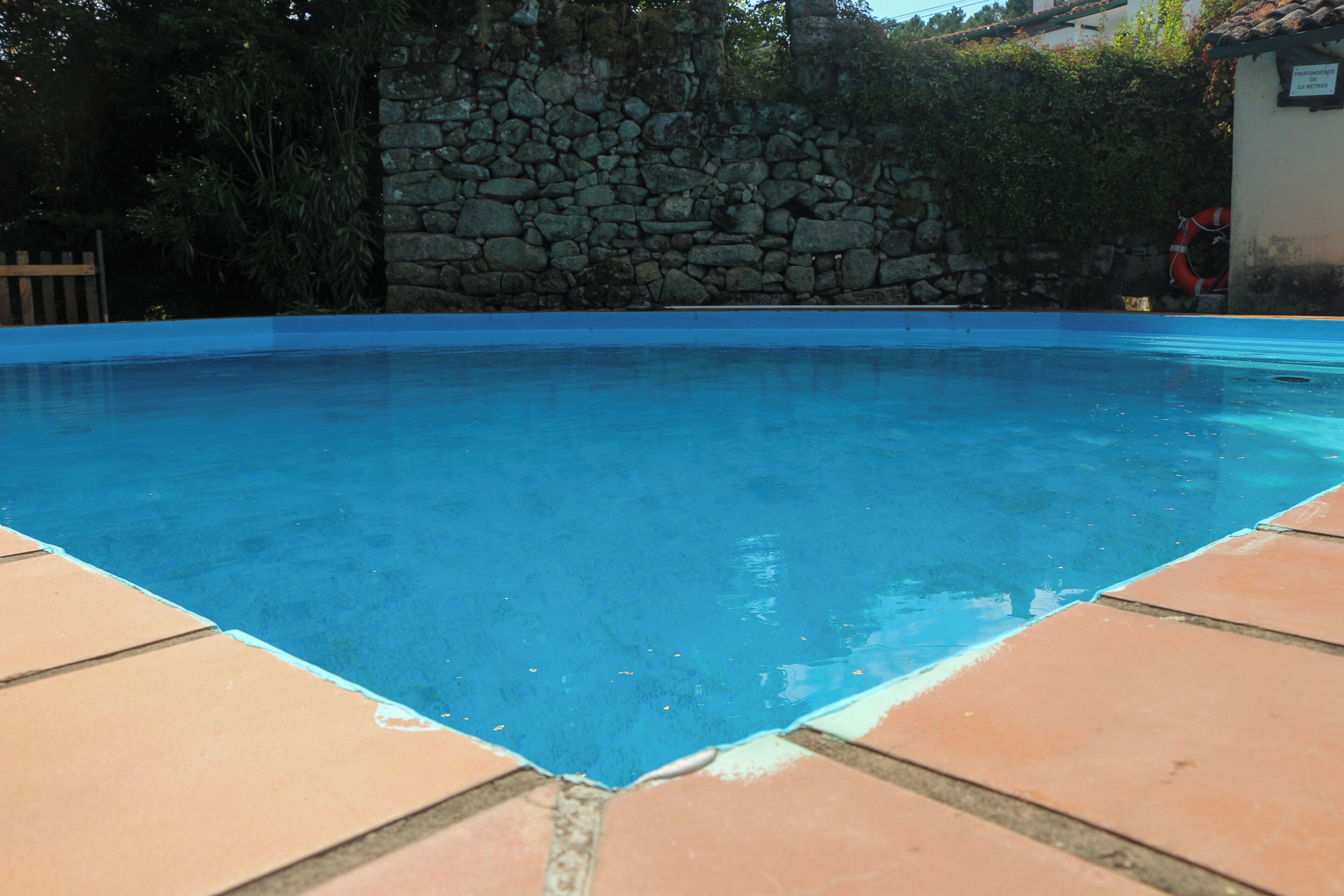 Una piscina amb mur de pedra i vores de rajola.