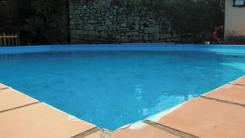 Una piscina amb mur de pedra i vores de rajola.