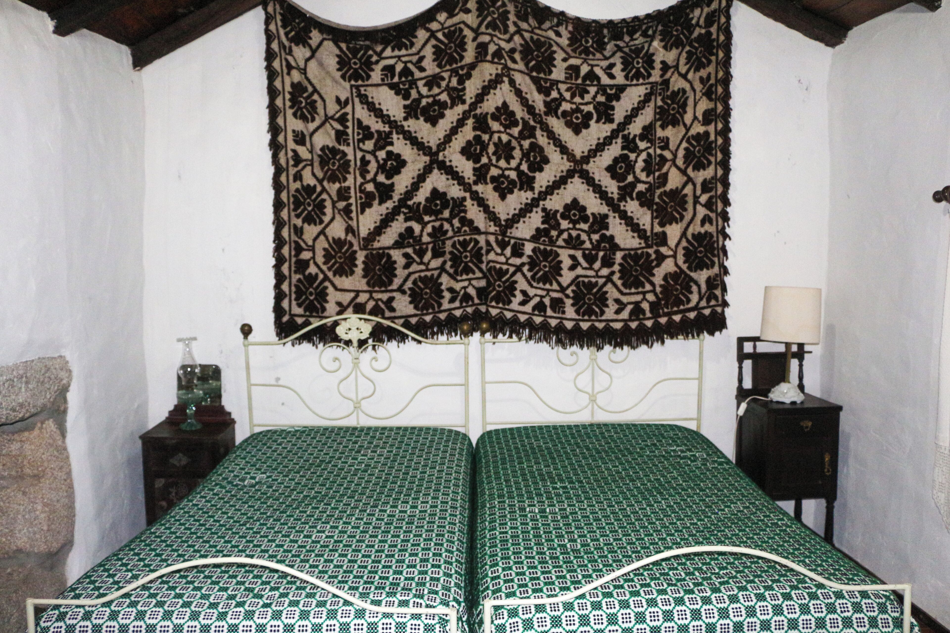Une chambre avec un lit, une table de chevet, une lampe et une tapisserie.