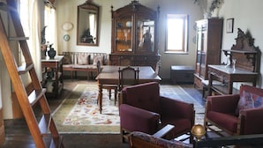 A traditional room with a wooden table, two armchairs, a mirror, and a cabinet. - Casa Campo das Bizarras (Castro Daire)