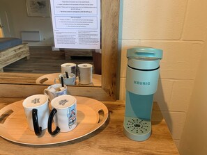 Un petit coin cuisine équipé d’une machine à café Keurig, de tasses et d  ’un plateau contenant des ustensiles.