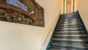 Un escalier menant à une pièce dont la porte est marquée de l’inscription « Suites », avec une enseigne décorative au-dessus.