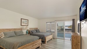 Een moderne slaapkamer met twee houten bedden, een groot raam en een flatscreen televisie aan de muur.