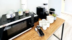 A kitchenette with a microwave, coffee maker, and storage jars. - Bay Tree cozy studio in Little River (Little River)