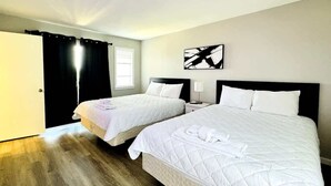 A hotel room with two beds, a black and white abstract painting on the wall, and a wooden floor. - Bay tree lovely one bedroom condo (Little River)