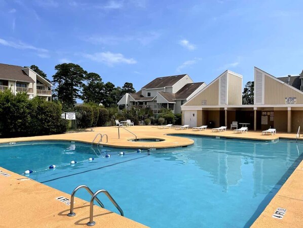 A swimming pool with a lifeguard tower, lounge chairs, and a building with a sign. - Bay Tree cozy studio with pool (Little River)
