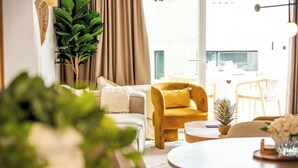 A modern living room with a sofa, a yellow armchair, a coffee table, and a potted plant.