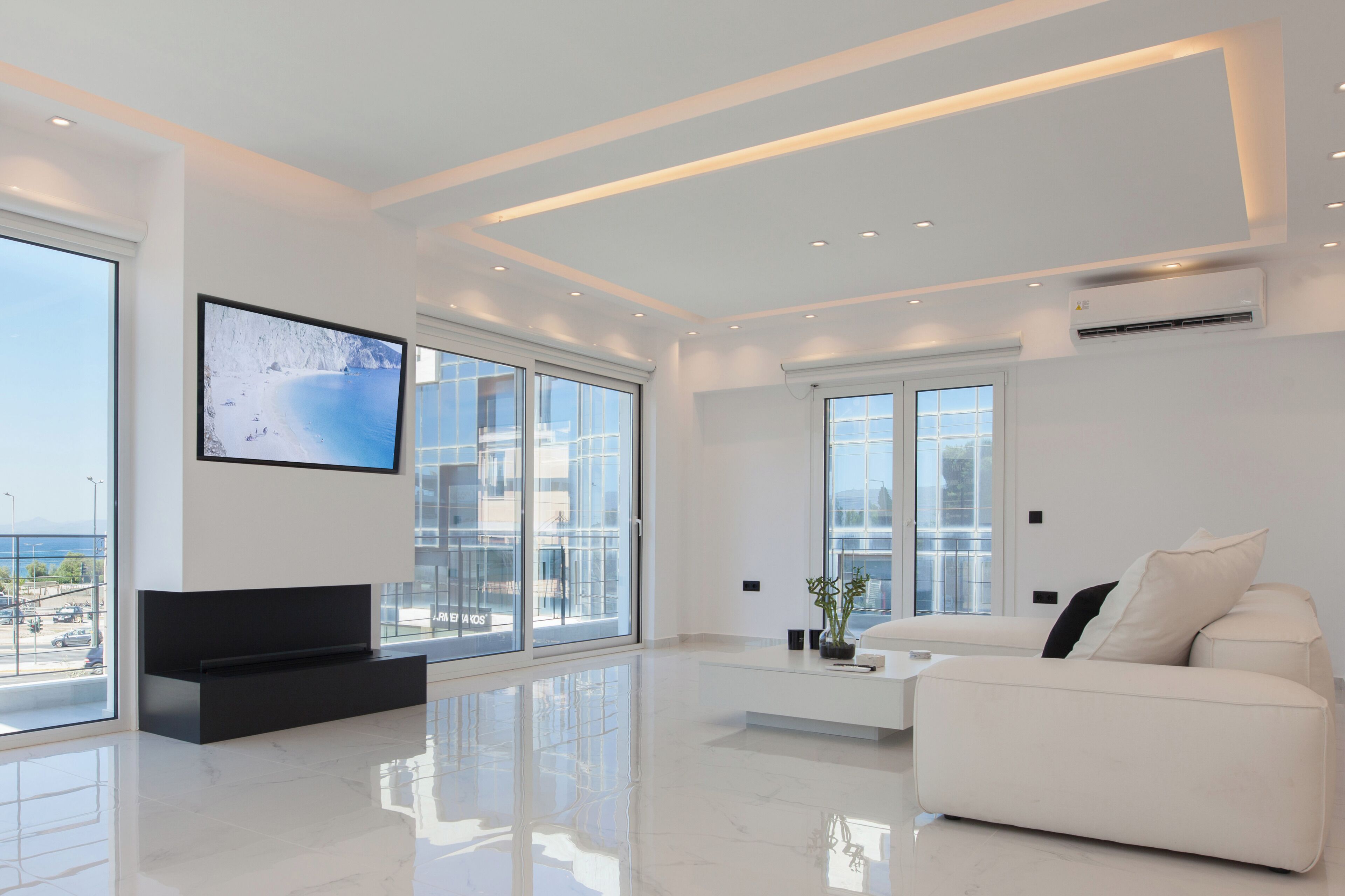 A modern living room with a large flat-screen TV, a white sofa, and a coffee table.