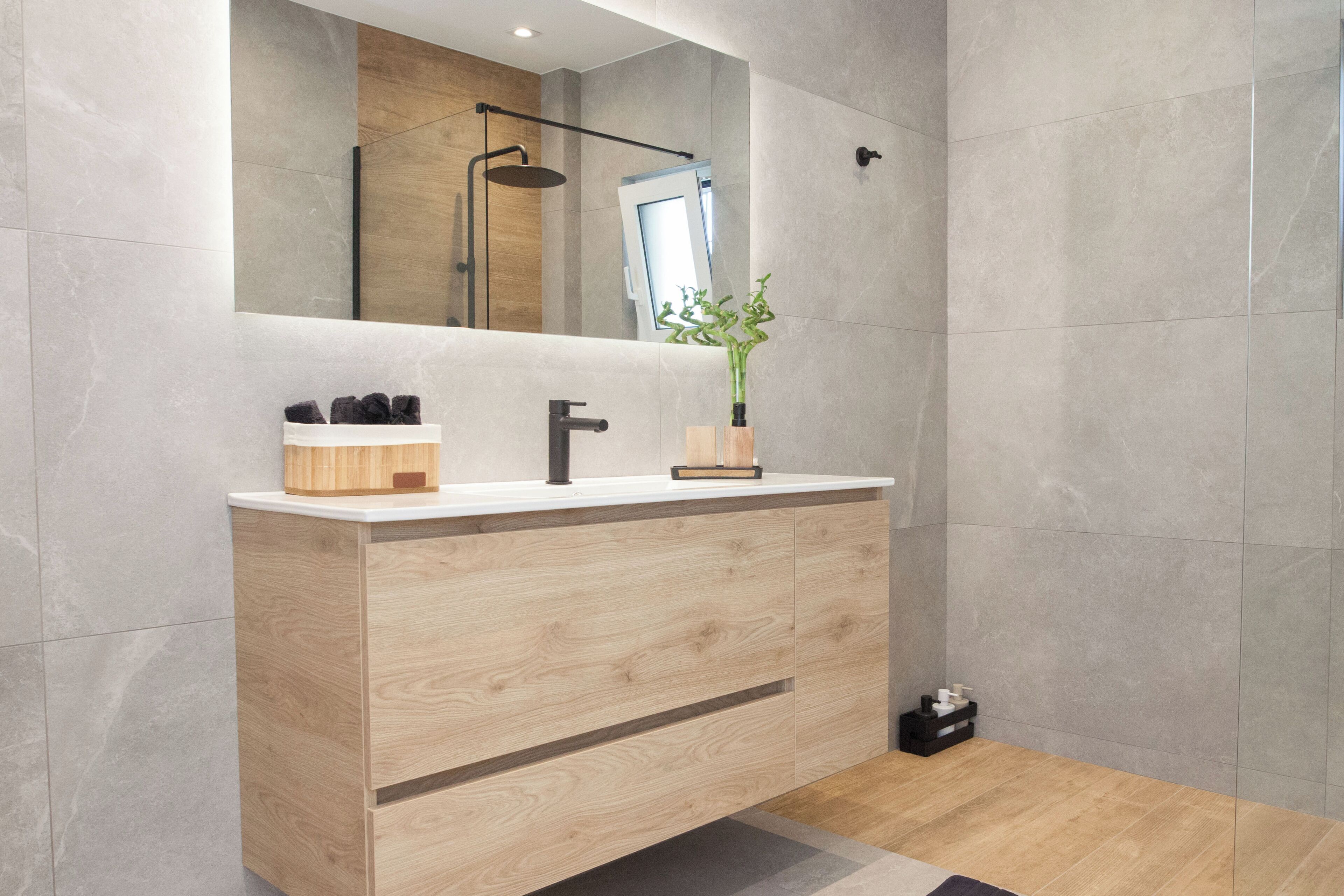 Ein modernes Badezimmer mit einem Holzkosmetikschrank, einem Spiegel und einer Duschkabine.