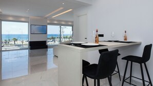 Eine moderne Küche mit einer großen Kochinsel, schwarzen Barhocker und Blick auf den Strand.
