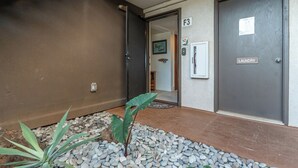 A hallway with a door labeled "F3" and a "Laundry" sign, a potted plant, and a small indoor garden area. - Ma'alaea Surf Unit F3-1 BR Ground Floor Beachfront Condo, Wi-Fi, AC, Pool, TV (Kihei)