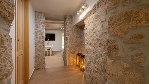 A hallway with stone walls, wooden flooring, and a dining area in the background. - Casa di Nika Stone Villa With Pool & Jacuzzi (Vinodol)