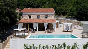 A two-story stone building with a red-tiled roof, a swimming pool, and outdoor seating with umbrellas. - Casa di Nika Stone Villa With Pool & Jacuzzi (Vinodol)