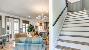 A modern living room with a sofa, a dining area, and a staircase. - Just Peachy (Carlton landing)