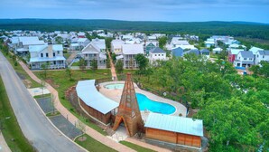 A residential area with a swimming pool, a unique wooden structure, and houses with various roof styles. - Just Peachy (Carlton landing)