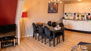 Un espacio habitable compacto con comedor, televisor y kitchenette.
