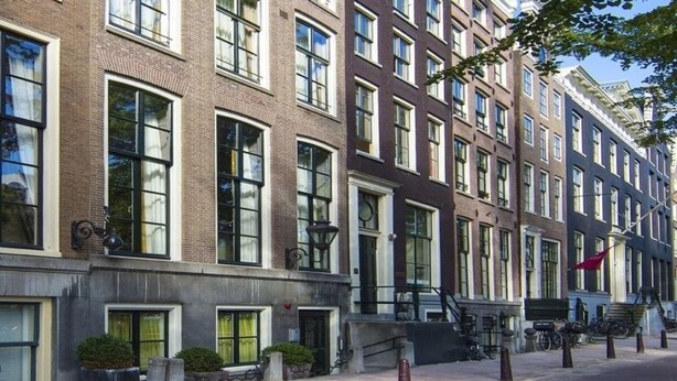 Una hilera de edificios de varios pisos con amplias ventanas, una escalera a la vista y zonas de estar al aire libre.