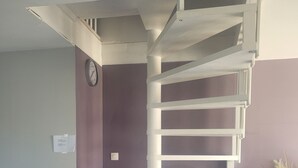 A spiral staircase in a room with a checkered floor, a clock on the wall, and a shelf with a vase of flowers. - La Cadole House surrounded by a vineyard. Panoramic trails. (Baroville)