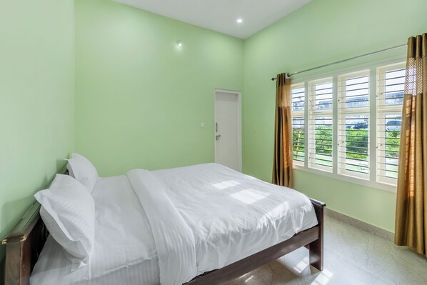 Une chambre à coucher avec un lit, une fenêtre avec des rideaux et une porte.