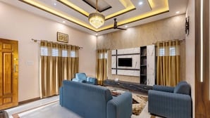 Uma sala de estar moderna com sofá, televisão de tela plana na parede e um lustre.