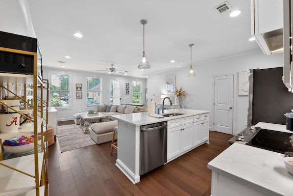 A modern kitchen with a central island, white cabinetry, and a dining area with a sofa and coffee table.