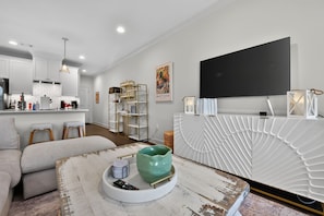 A modern living room with a sofa, a coffee table, and a kitchen area in the background.