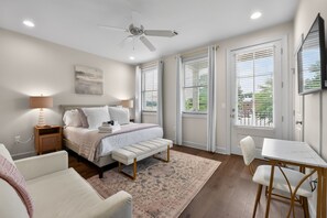 A bedroom with a bed, bedside tables, a desk, a chair, a ceiling fan, and a window with blinds. - Coastal Tide - Luxury Townhome - Book for Football Season! (Tuscaloosa)