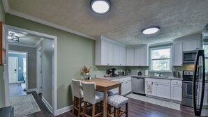 Eine moderne Küche mit weißen Schränken, einem Holzespeisetisch und einem eingebauten Backofen.