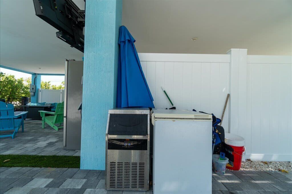 An outdoor patio area with a grill, a refrigerator, and outdoor seating.