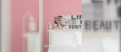 A bedroom with a bed, a wall-mounted light, and a decorative piece with text.