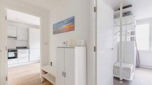 A modern kitchen with white cabinets, a built-in oven, and a painting on the wall. - Chic 1BD Flat in the Heart of Islington! (Greater London)