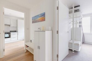 A modern kitchen with white cabinets, a built-in oven, and a painting on the wall. - Chic 1BD Flat in the Heart of Islington! (Greater London)
