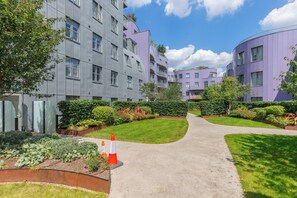 A modern residential building with a curved facade, a central pathway, and well-maintained gardens. - Chic 1BD Flat in the Heart of Islington! (Greater London)