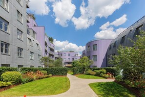 A modern residential building with a curved facade, a central courtyard, and a clear sky. - Chic 1BD Flat in the Heart of Islington! (Greater London)