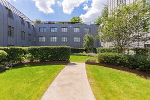 A pathway leading to a modern building with multiple windows and a flat roof. - Chic 1BD Flat in the Heart of Islington! (Greater London)