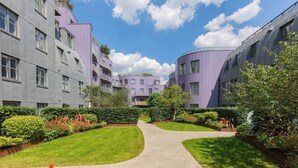 A modern residential building with a curved facade, a central pathway, and well-maintained greenery. - Chic 1BD Flat in the Heart of Islington! (Greater London)