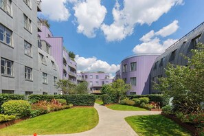 A modern residential building with a curved facade, a central pathway, and well-maintained greenery. - Chic 1BD Flat in the Heart of Islington! (Greater London)
