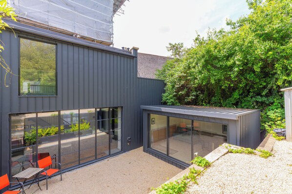 A modern building with large windows and a patio area with outdoor seating.