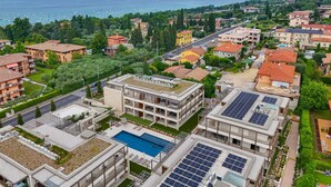 A residential area with a view of the sea, featuring apartment buildings, a swimming pool, and solar panels. - MGH Luxury - Corte Garden Bardolino 34 (Bardolino)