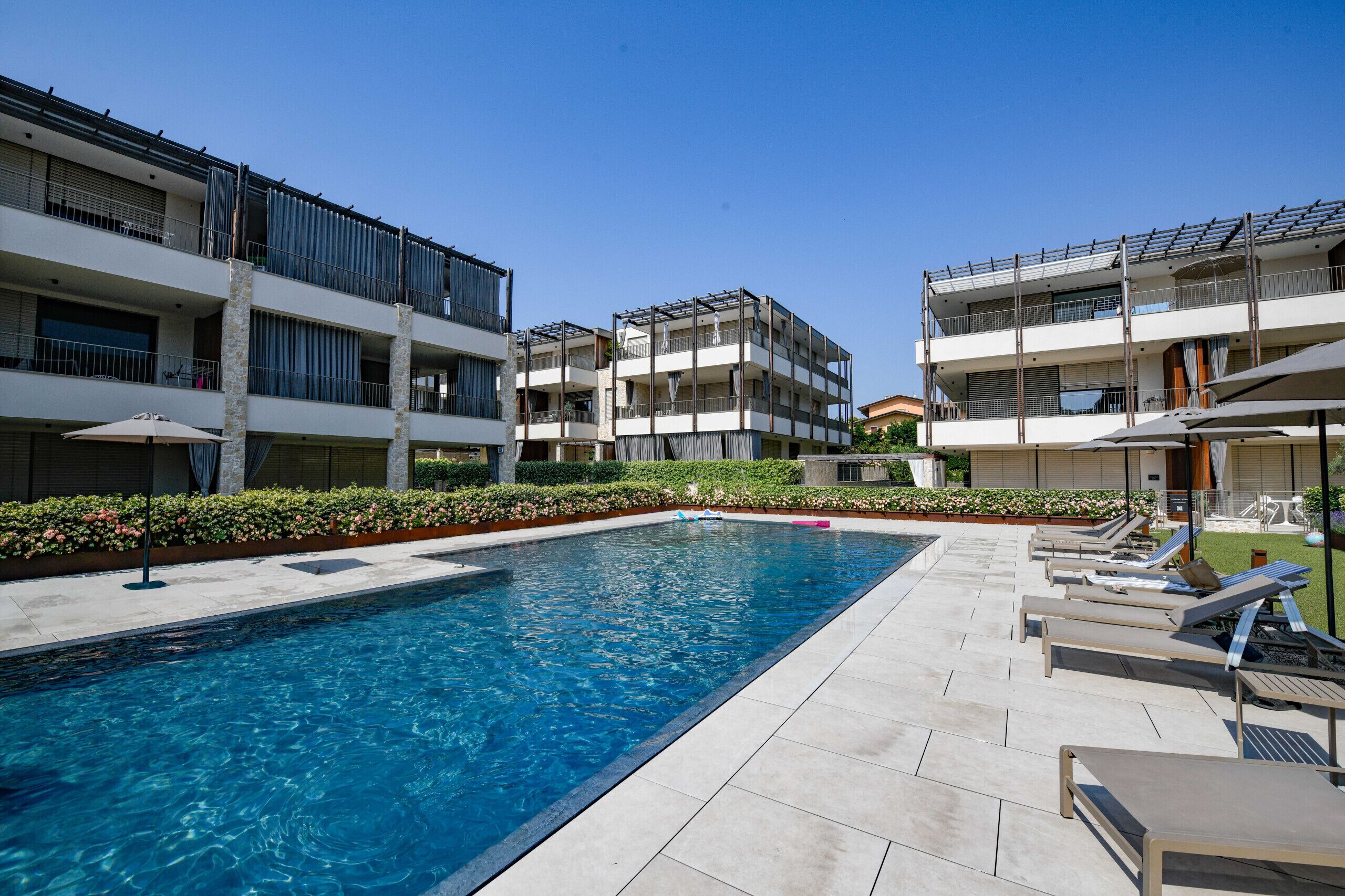 A swimming pool with lounge chairs and a clear blue sky.