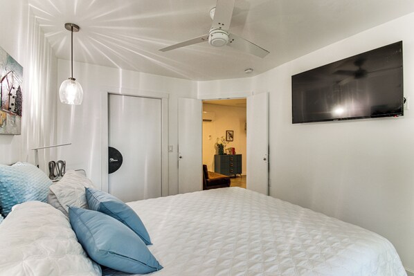 A bedroom with a bed, a ceiling fan, a TV, and a door leading to another room. - Shawnee Cabin w/ On-site Reservoir Access! (Shawnee)