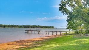 Un muelle de madera se adentra en un lago tranquilo, rodeado de zonas verdes y árboles.