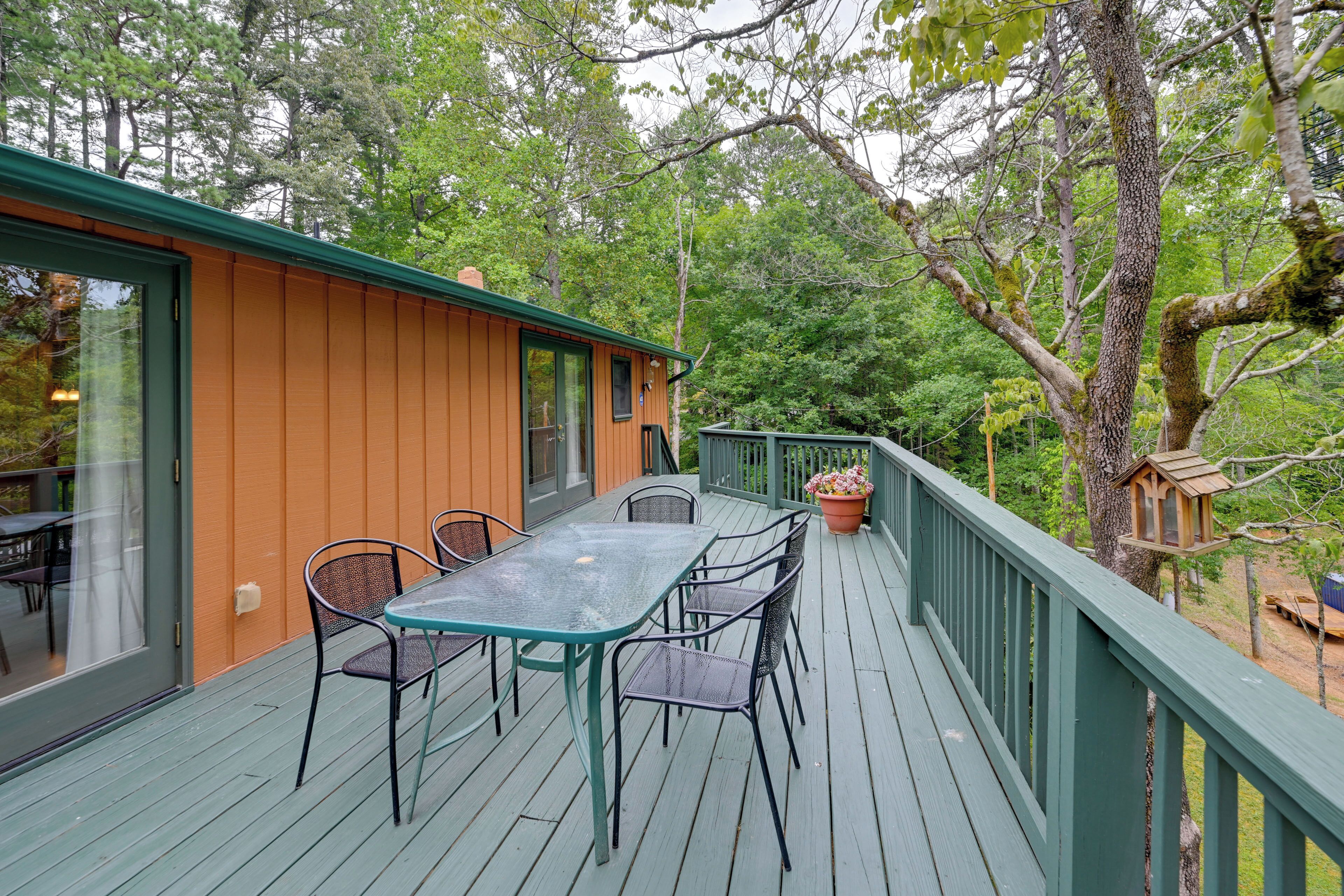 A wooden deck with a glass door, metal chairs, and a table.