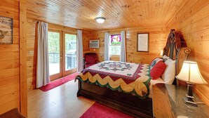 Une chambre dans une cabane en bois, avec un lit, une chaise, une lampe et une fenêtre.