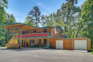 A two-story log cabin with a porch, a covered front area, and a flag.