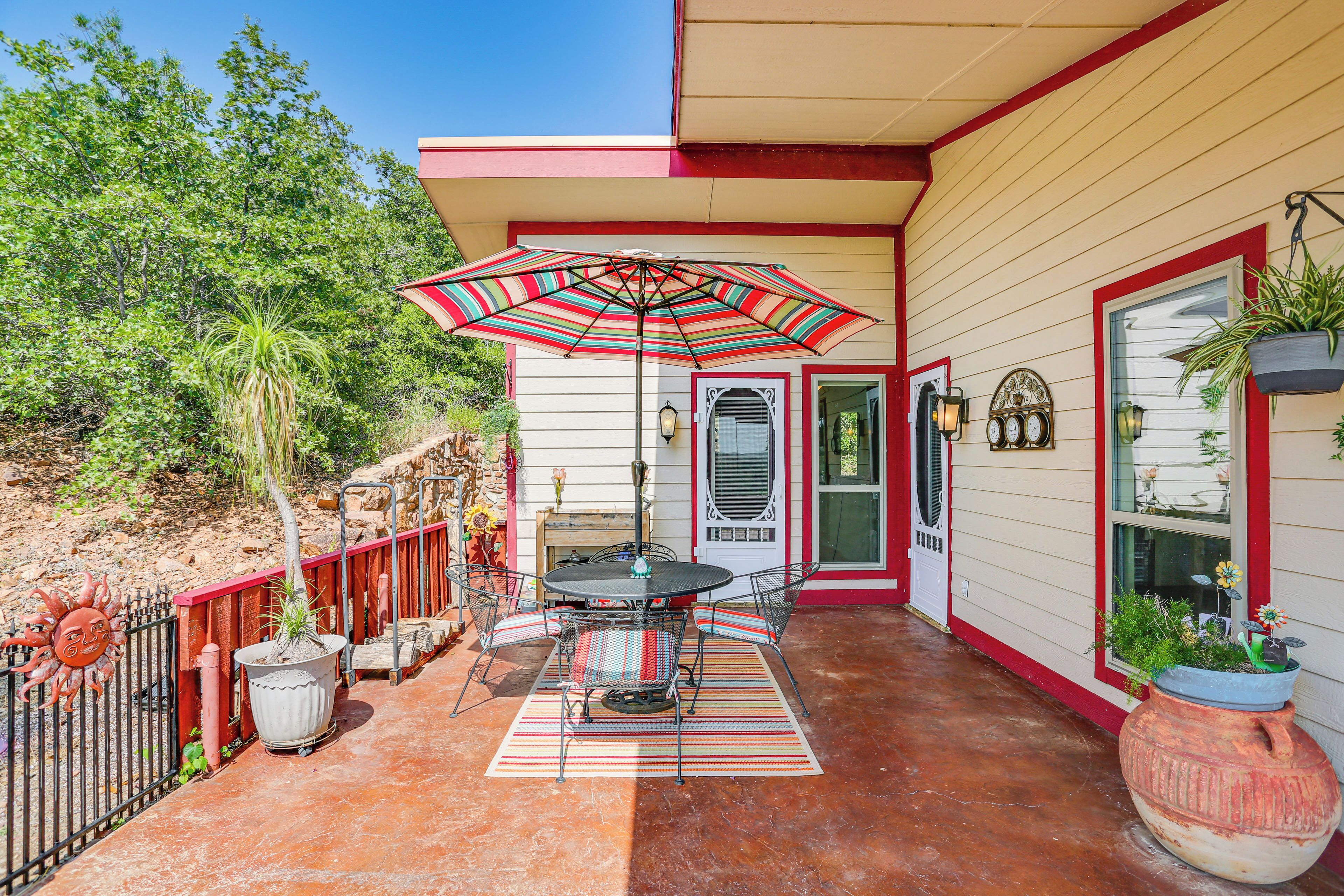 A patio with a table and chairs, a striped umbrella, and potted plants.